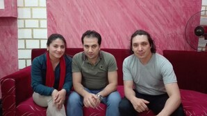 Three people seated on a red couch with a brick-patterned wall behind them. - The Emerald Hotel (Cairo)