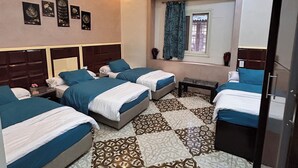 A hotel room with three beds, a window with curtains, an air conditioning unit, and a patterned floor. - The Emerald Hotel (Cairo)