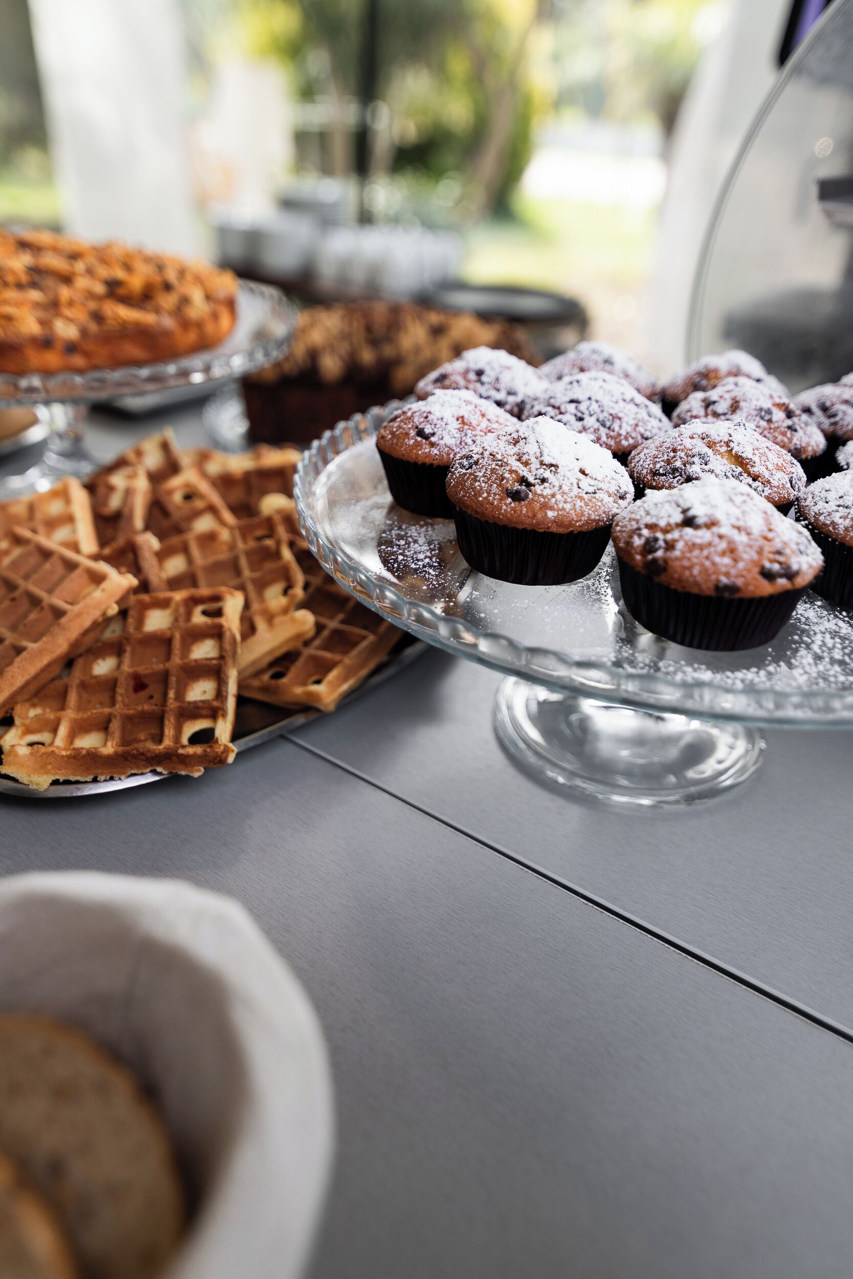 A buffet table with waffles, muffins, and a pie.