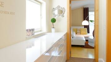 A modern hotel room with a large window, a bedside table, a lamp, and a bed with yellow pillows.
