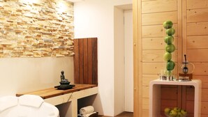 A modern bathroom with a stone wall, wooden paneling, a bathtub, a wooden shelf with towels, and a glass of water. - Aparthotel Vila Minka (Ljubljana)