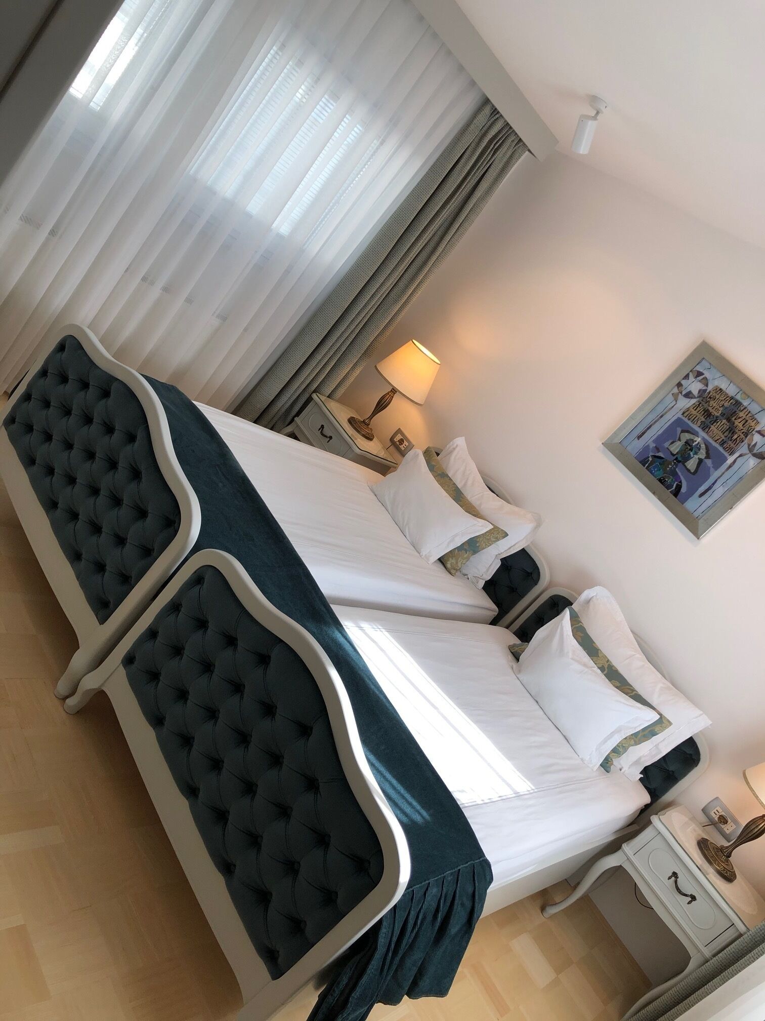 A hotel room with a large bed, a nightstand, a lamp, and a painting on the wall.
