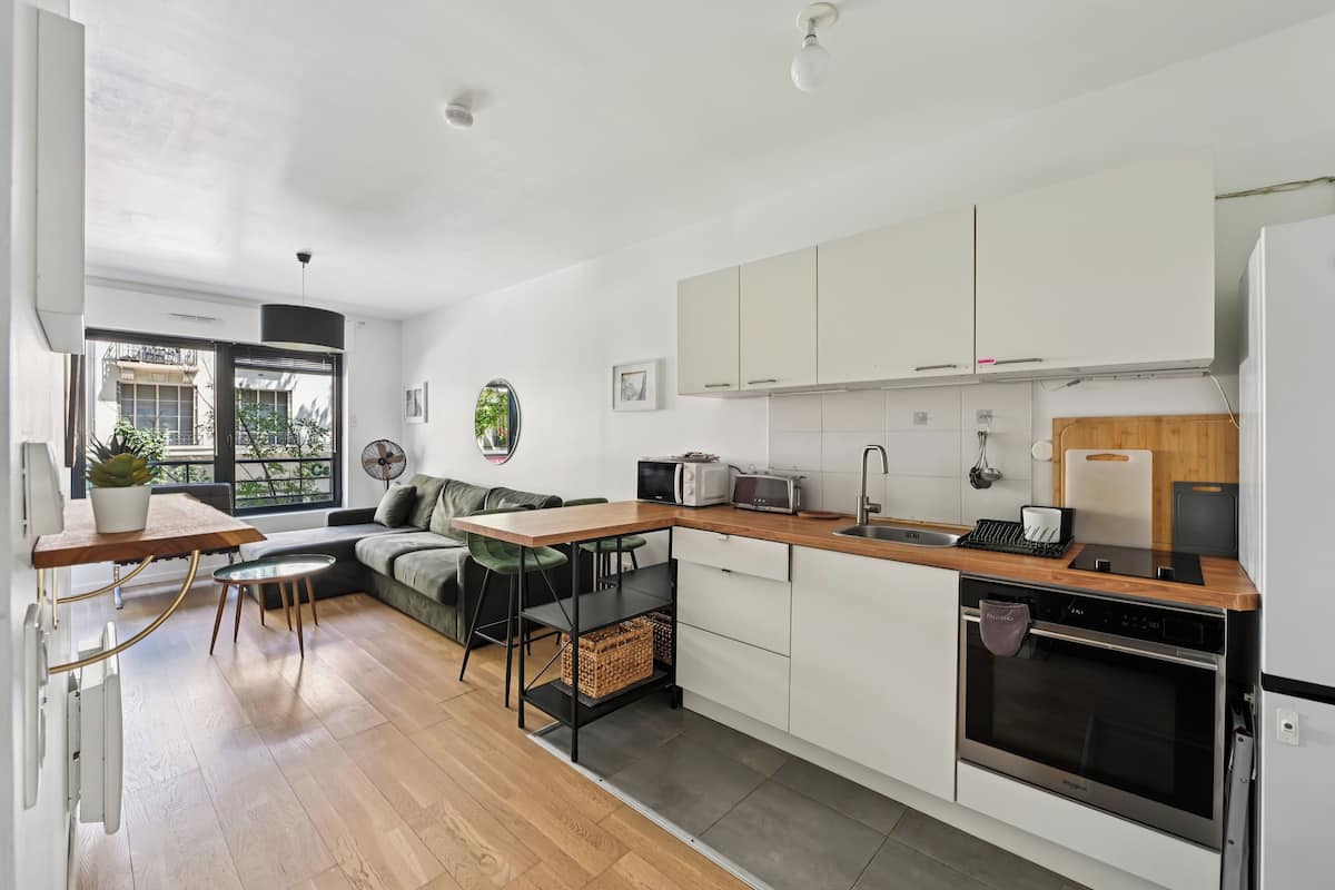 A modern kitchen with white cabinets, a wooden countertop, and a built-in oven.