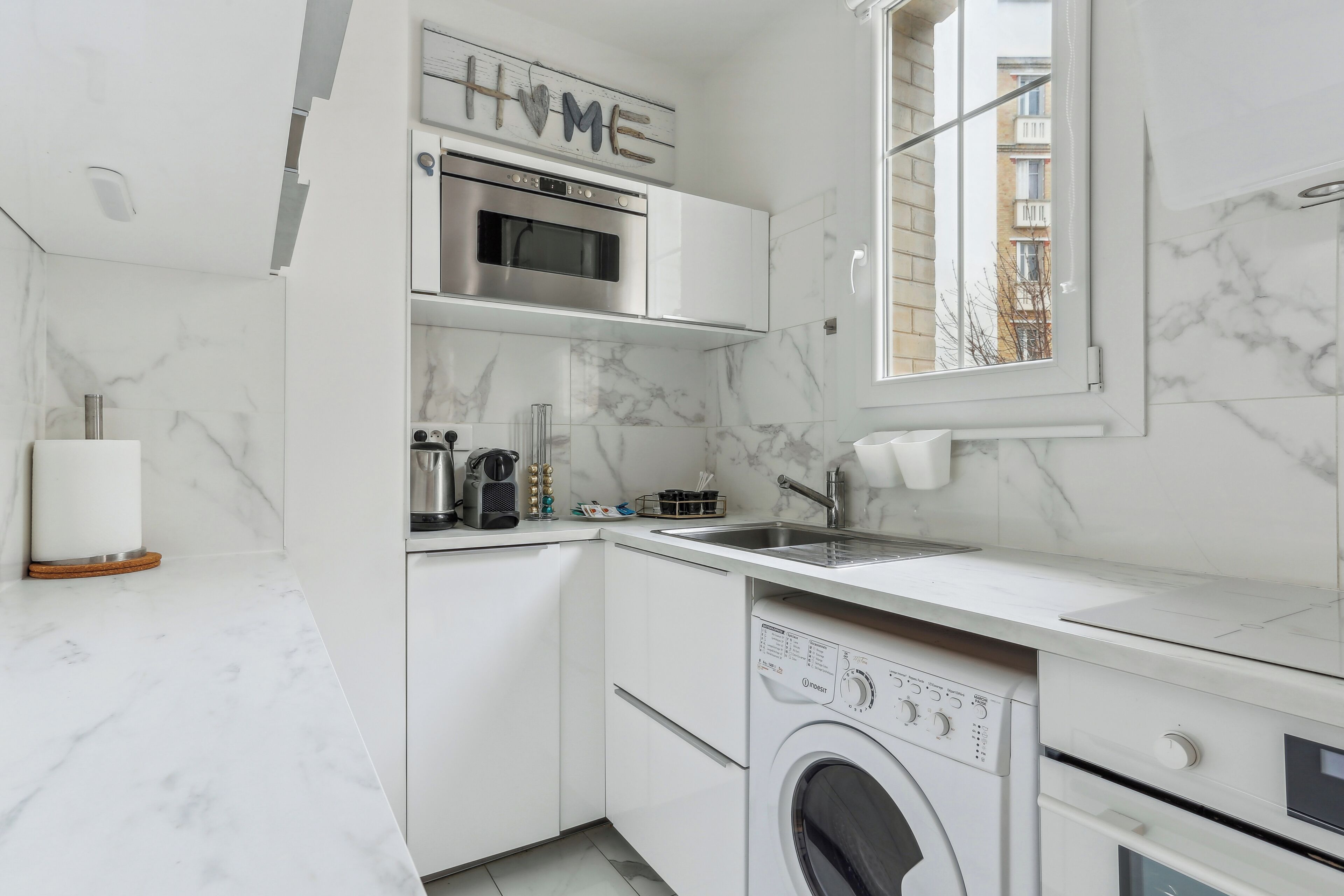 Een kleine keuken met een ingebouwde oven, magnetron en wasmachine.