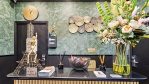 A reception desk with a clock, decorative wall art, a vase with flowers, and a small Buddha statue. - Résidence Aurmat Appart Hôtel Paris Boulogne (Boulogne-Billancourt)