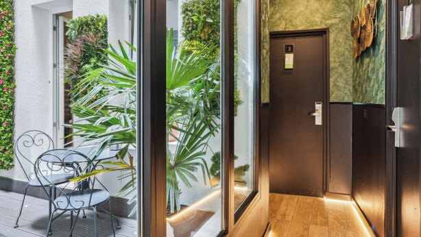 A modern hotel corridor with large windows, wooden flooring, and a green accent wall. - Résidence Aurmat Appart Hôtel Paris Boulogne (Boulogne-Billancourt)