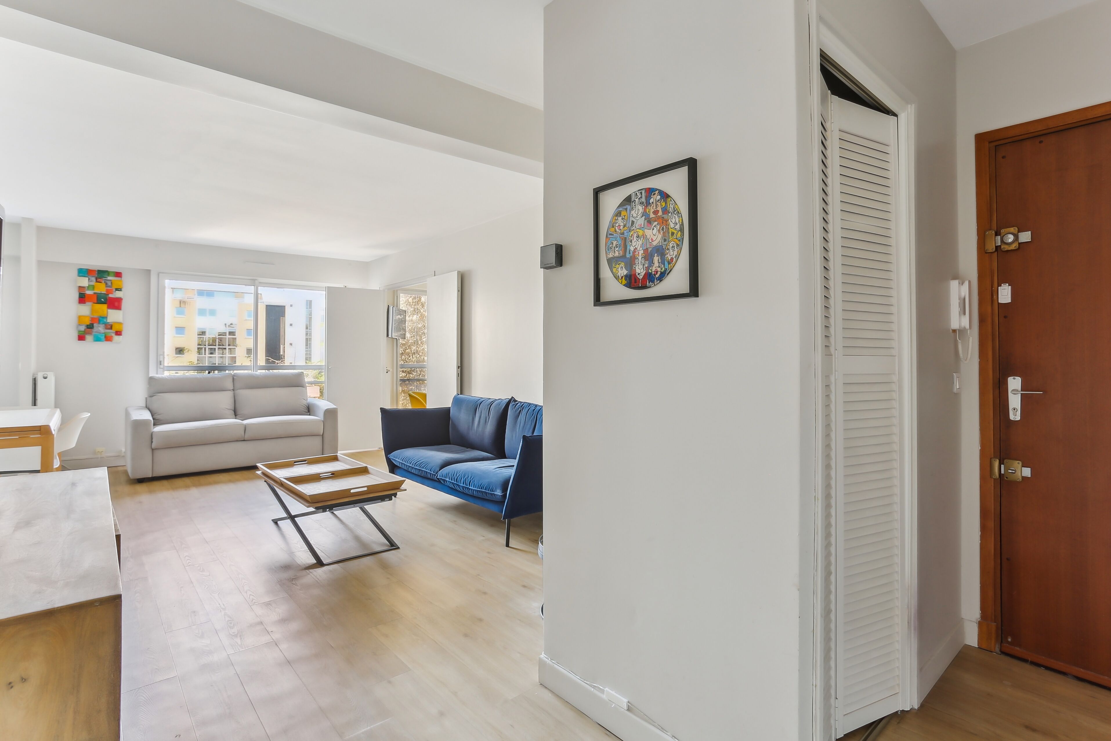 Una sala moderna con un sofá blanco, un sofá azul y una mesa de centro de madera.