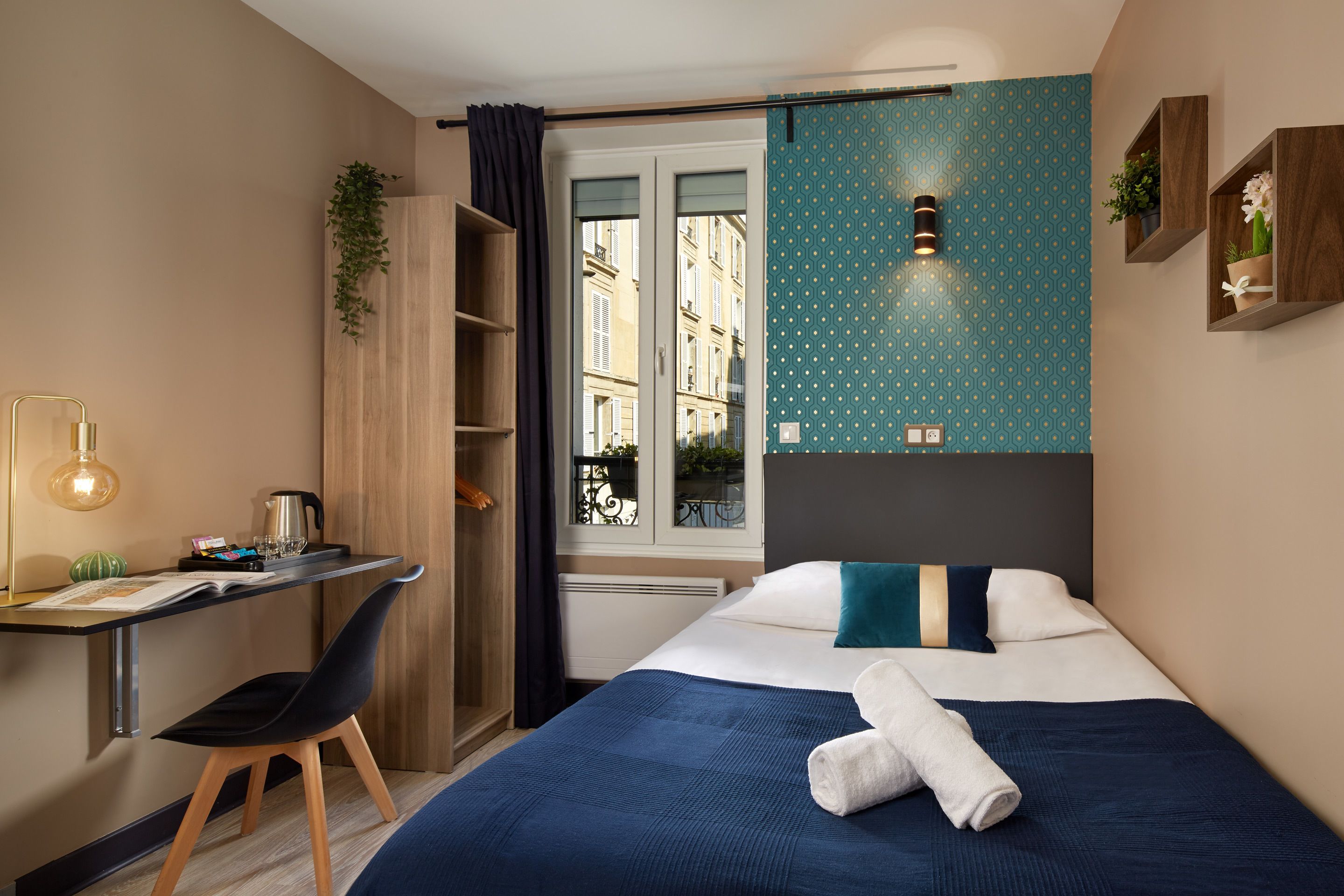 Une chambre d’hôtel moderne, équipée d’un lit, d’un bureau, d’une chaise et offrant une vue sur la ville par une fenêtre.