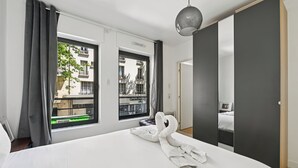 A modern hotel room with a large bed, a balcony view, and a wardrobe. - Résidence Aurmat Appart Hôtel Paris Boulogne (Boulogne-Billancourt)