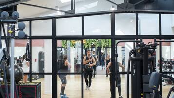 Un gimnasio con equipo de levantamiento de pesas, un espejo grande y suelo de madera.
