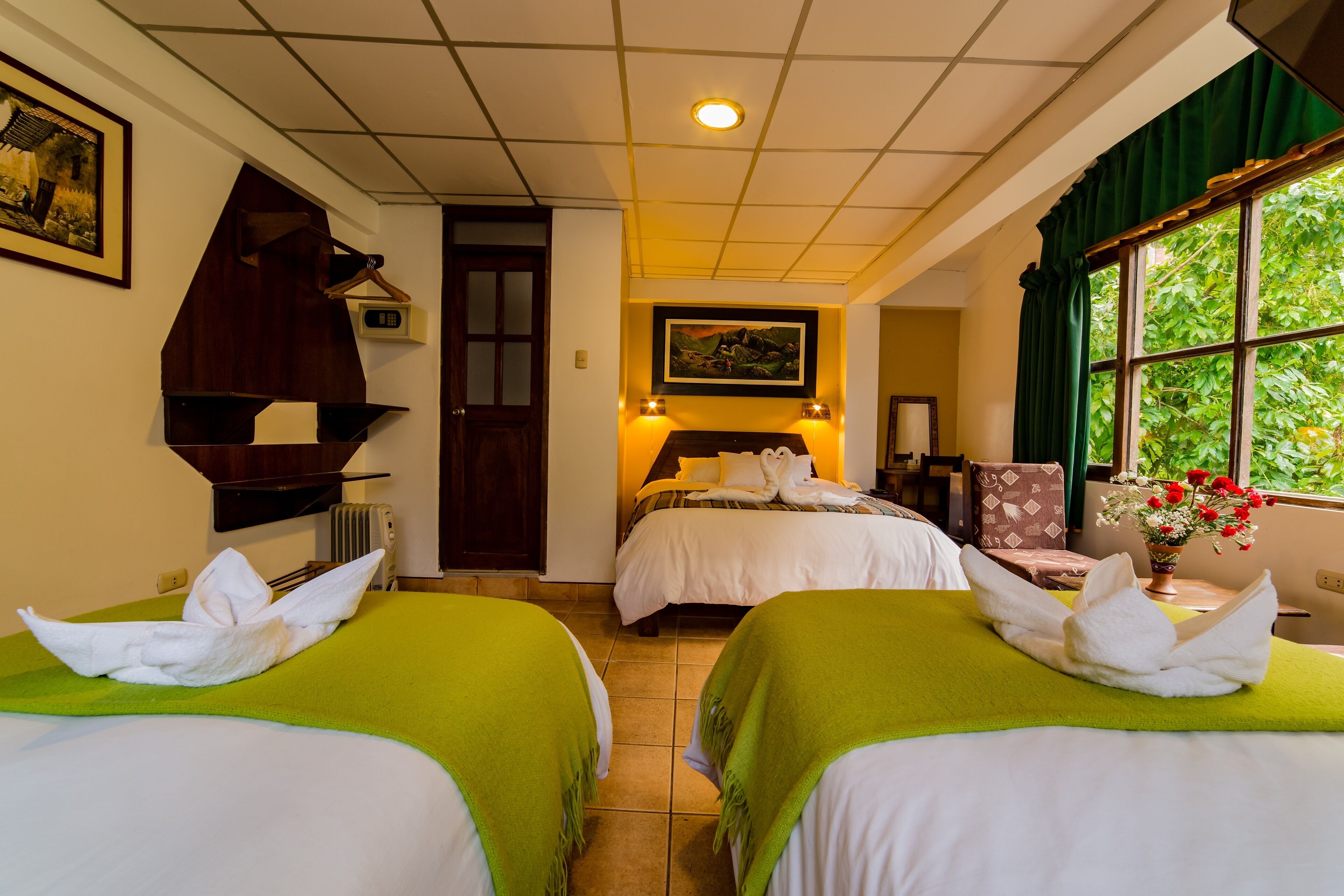 Habitación de hotel con dos camas, un cuadro en la pared, una ventana con cortinas y una puerta que da a otra habitación.
