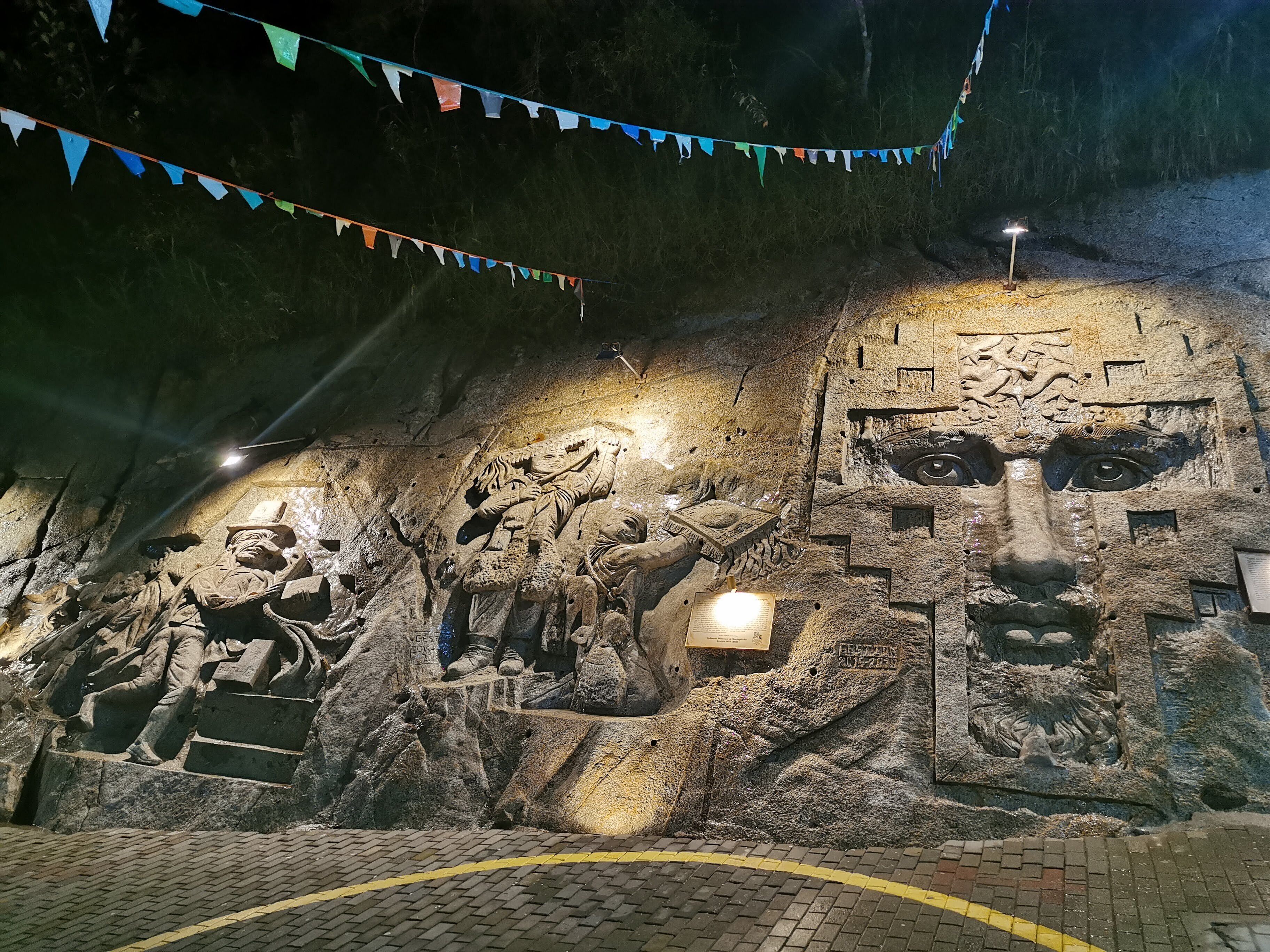 Une grotte ornée de gravures anciennes et abritant une grande sculpture représentant un visage.