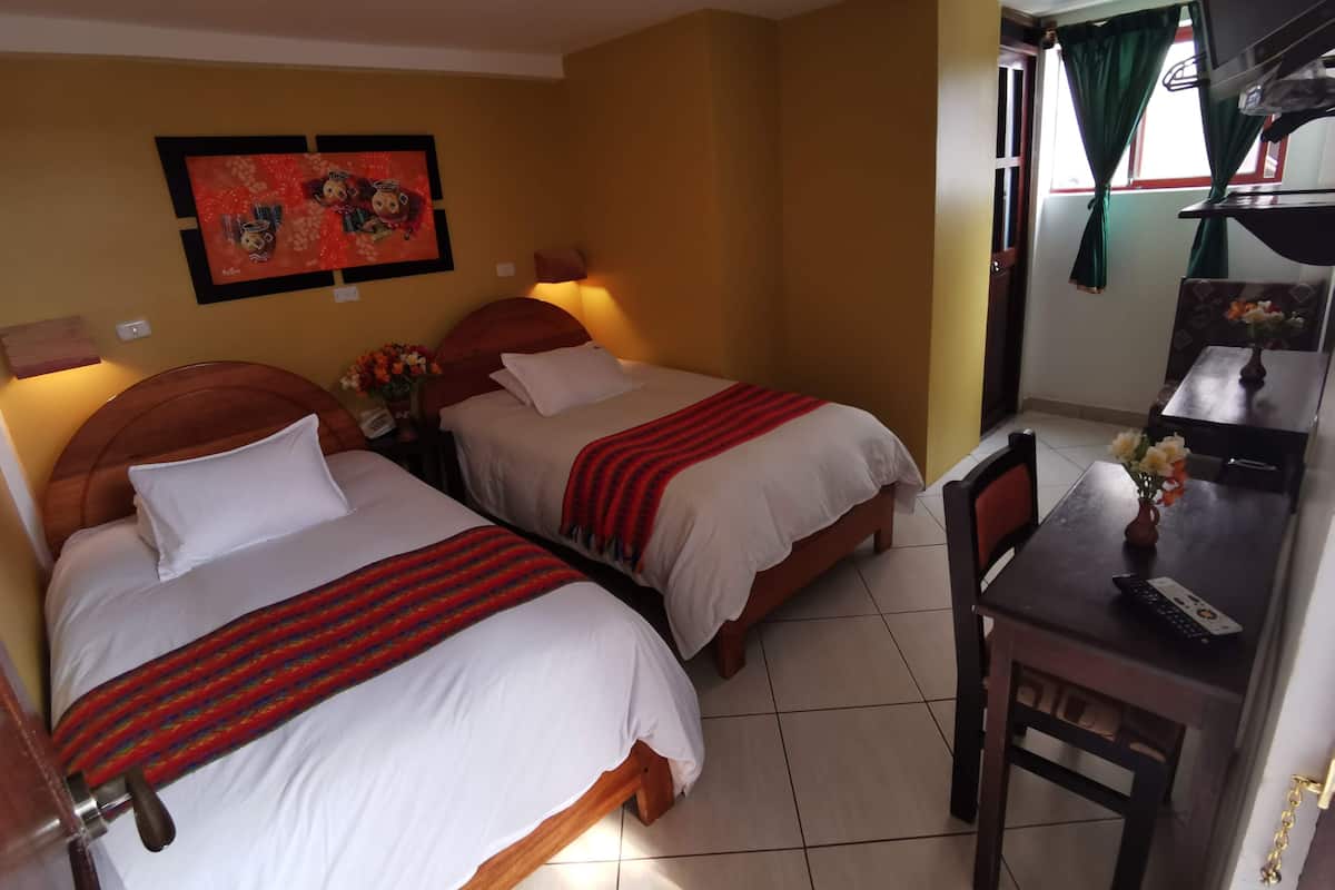 A hotel room with two beds, a desk, a chair, and a dining table.