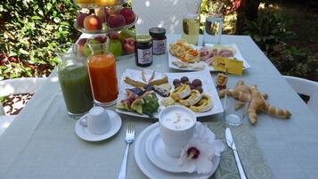 Una mesa al aire libre con diversas opciones de comida, entre ellas frutas, pasteles y bebidas.