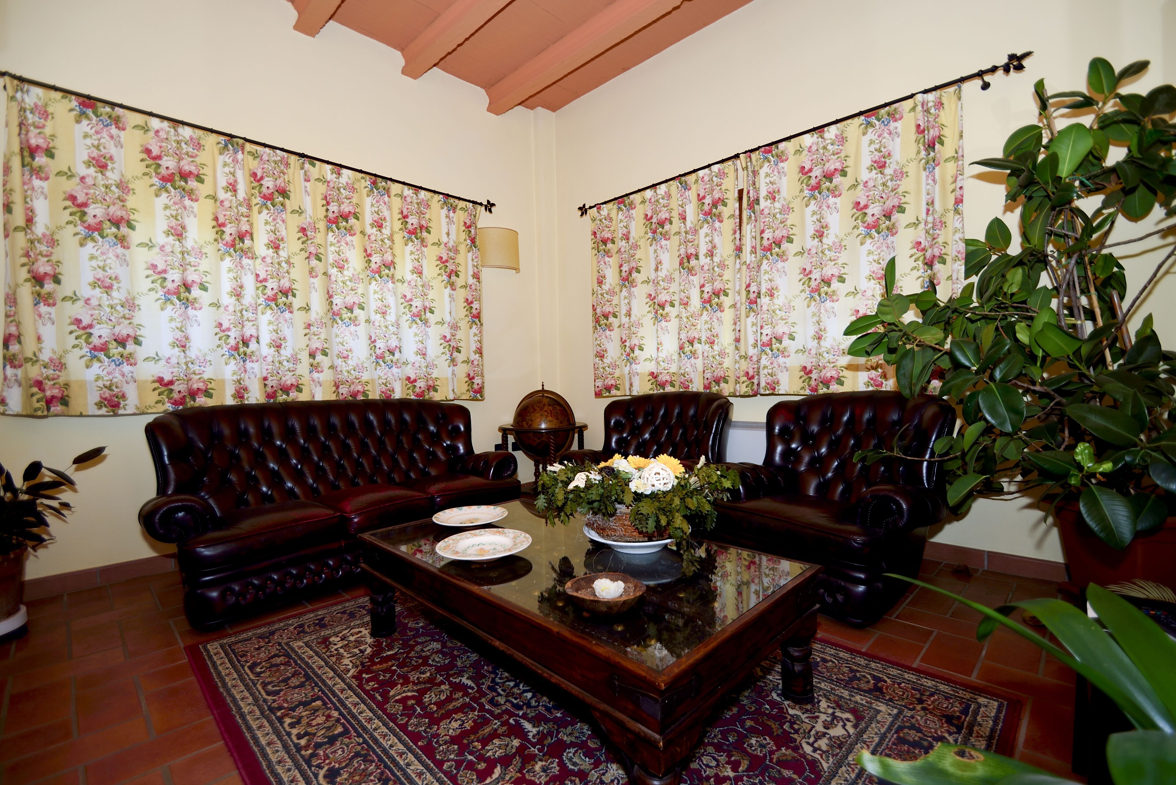 Una habitación con dos sofás de cuero, una mesa de centro con un centro de mesa floral y una planta en maceta.