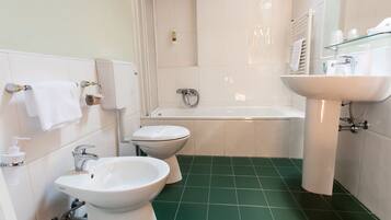 A bathroom with a bathtub, two sinks, and a toilet.