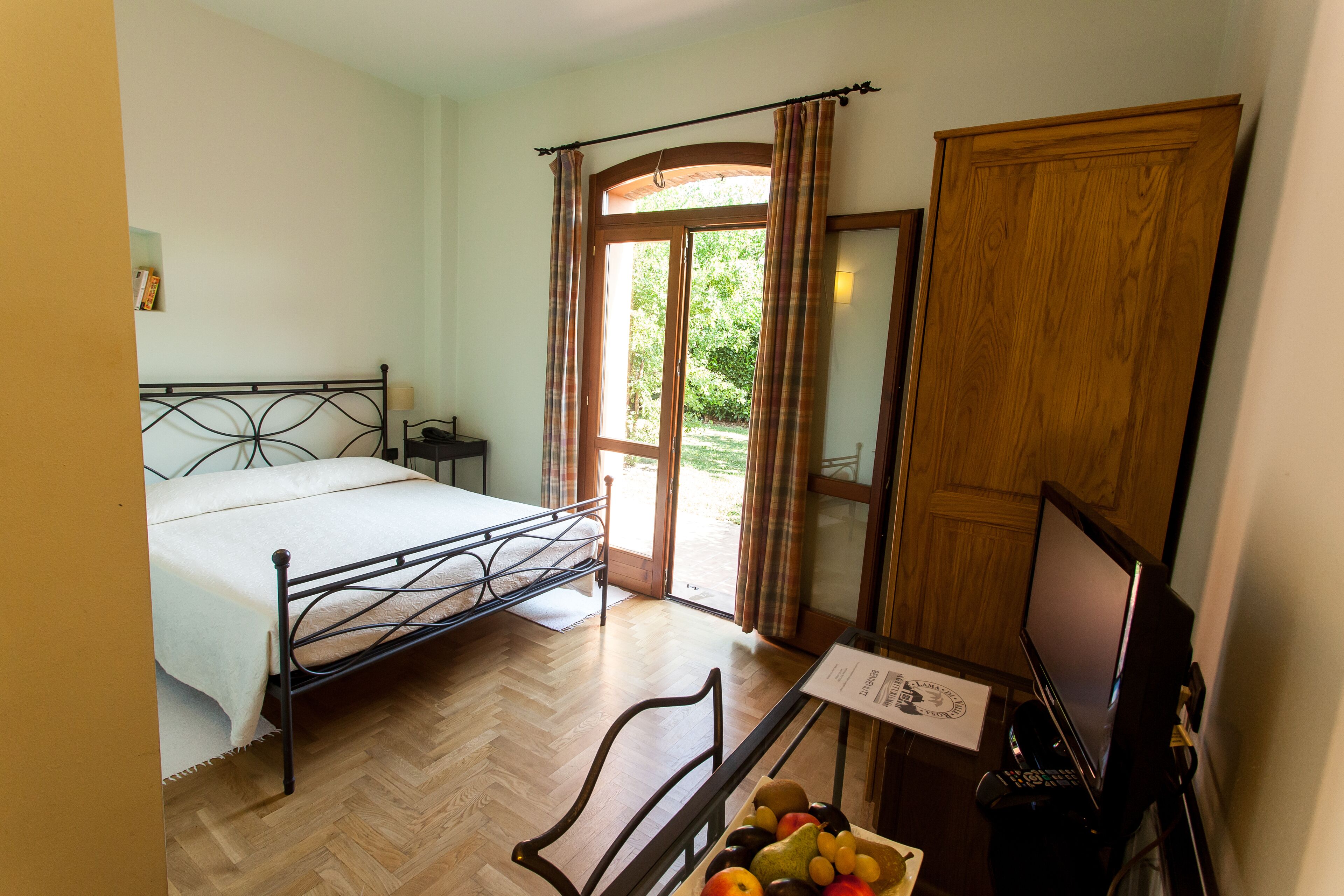 A bedroom with a bed, a desk with a computer, a chair, and a window with curtains.