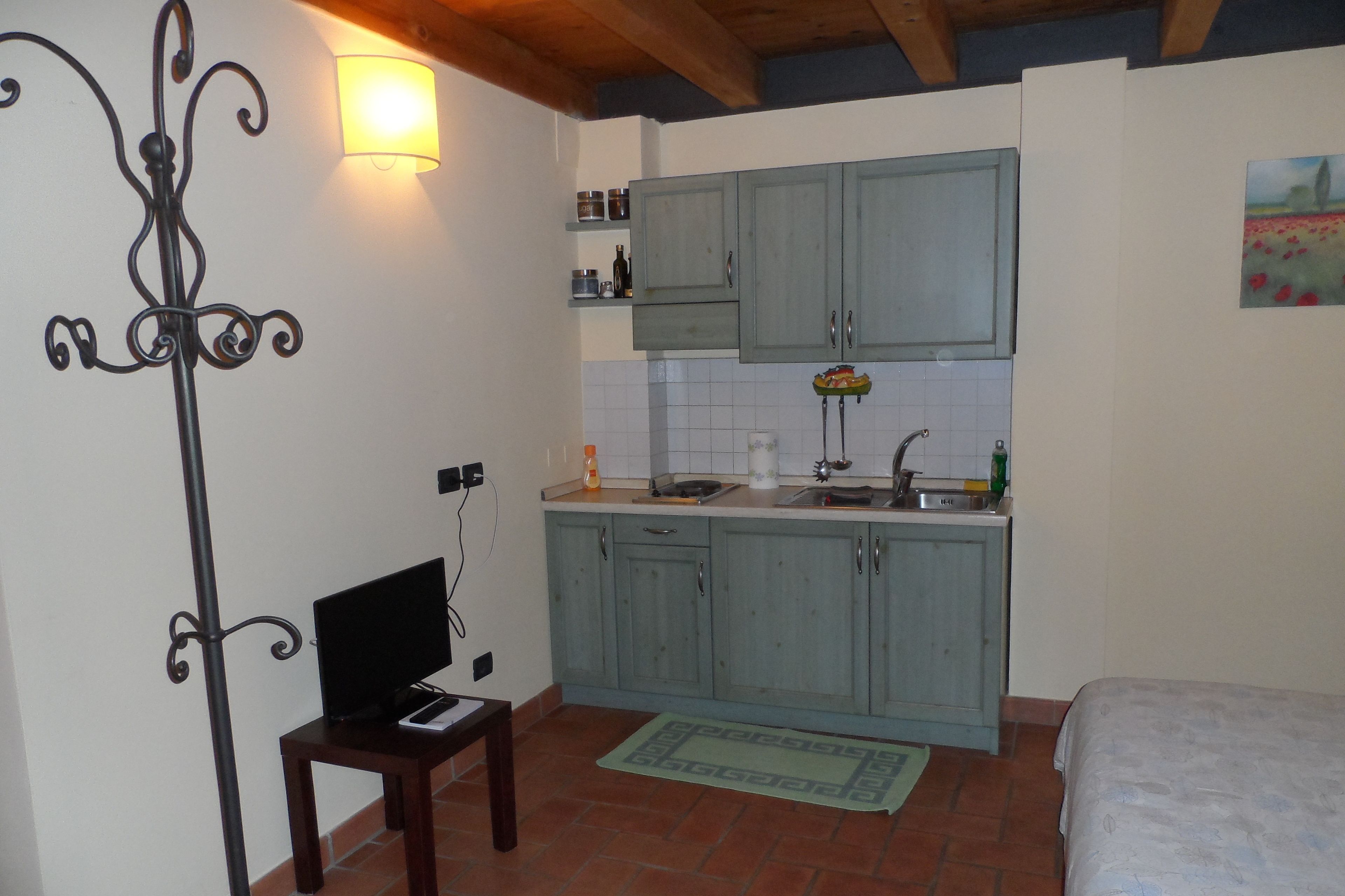 A compact kitchen with light blue cabinets, a small table, and a bed in the adjacent room.
