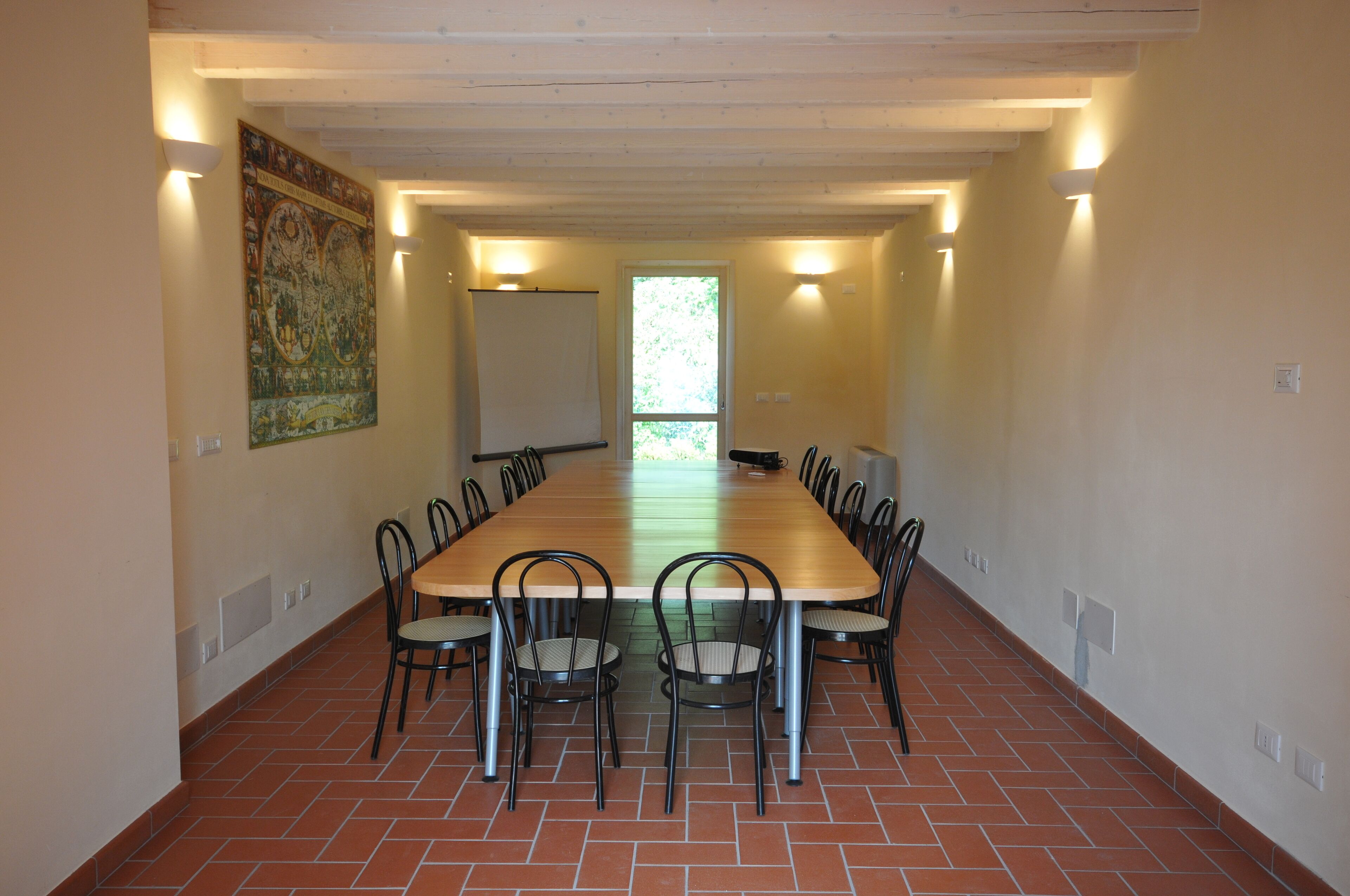 Een lange vergaderruimte met een houten tafel en stoelen, een whiteboard en een groot wandtapijt.
