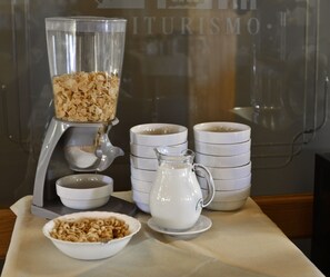 A breakfast setup with a blender, bowls, and a pitcher on a table.