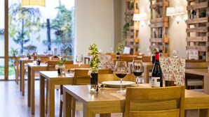 Een restaurant met houten tafels en stoelen, wijnkleden en een fles wijn op tafel.