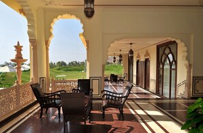 A corridor with a view of a green landscape, featuring traditional arches and a patterned floor. - Rajasthali Resort and Spa (Amer)
