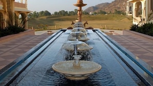 Une fontaine d’eau dans une cour, avec vue sur un paysage vallonné.