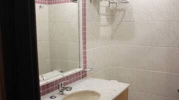 Baño con lavamanos, espejo y perchero para toallas.