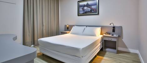 Una habitación de hotel moderna con una cama grande, un escritorio y una mesita de noche.