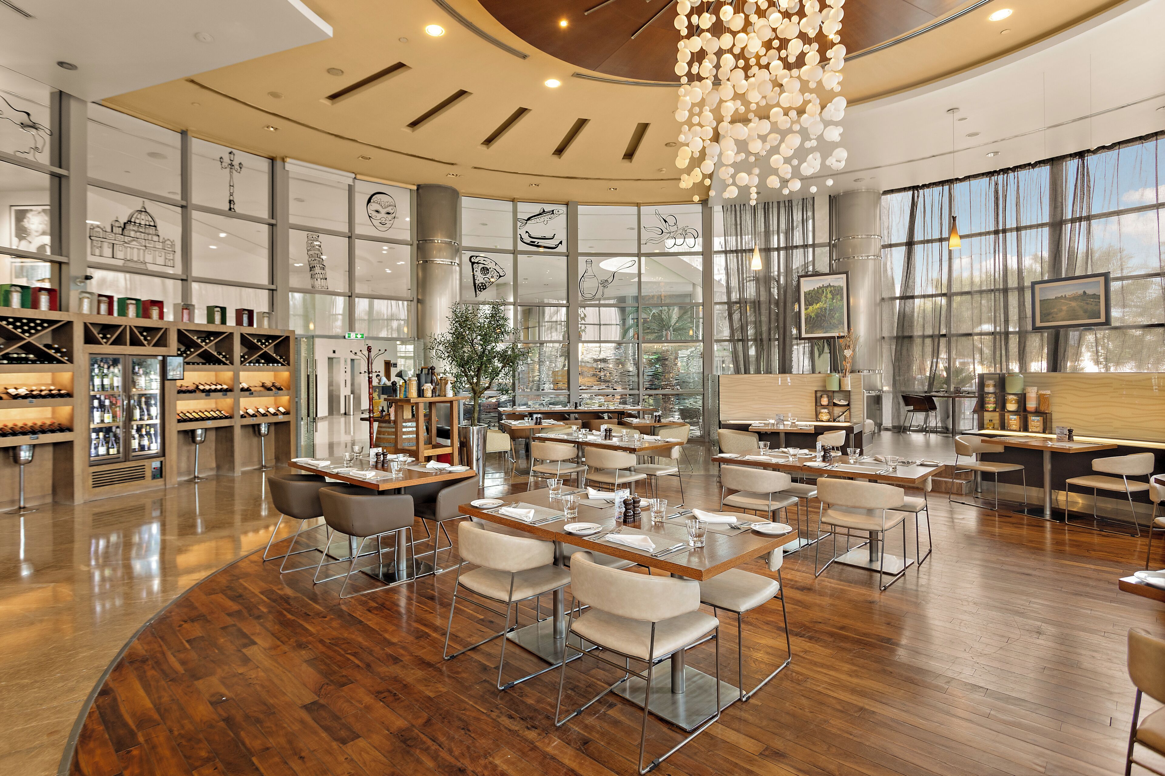 A spacious restaurant with wooden flooring, multiple dining tables, and chairs.
