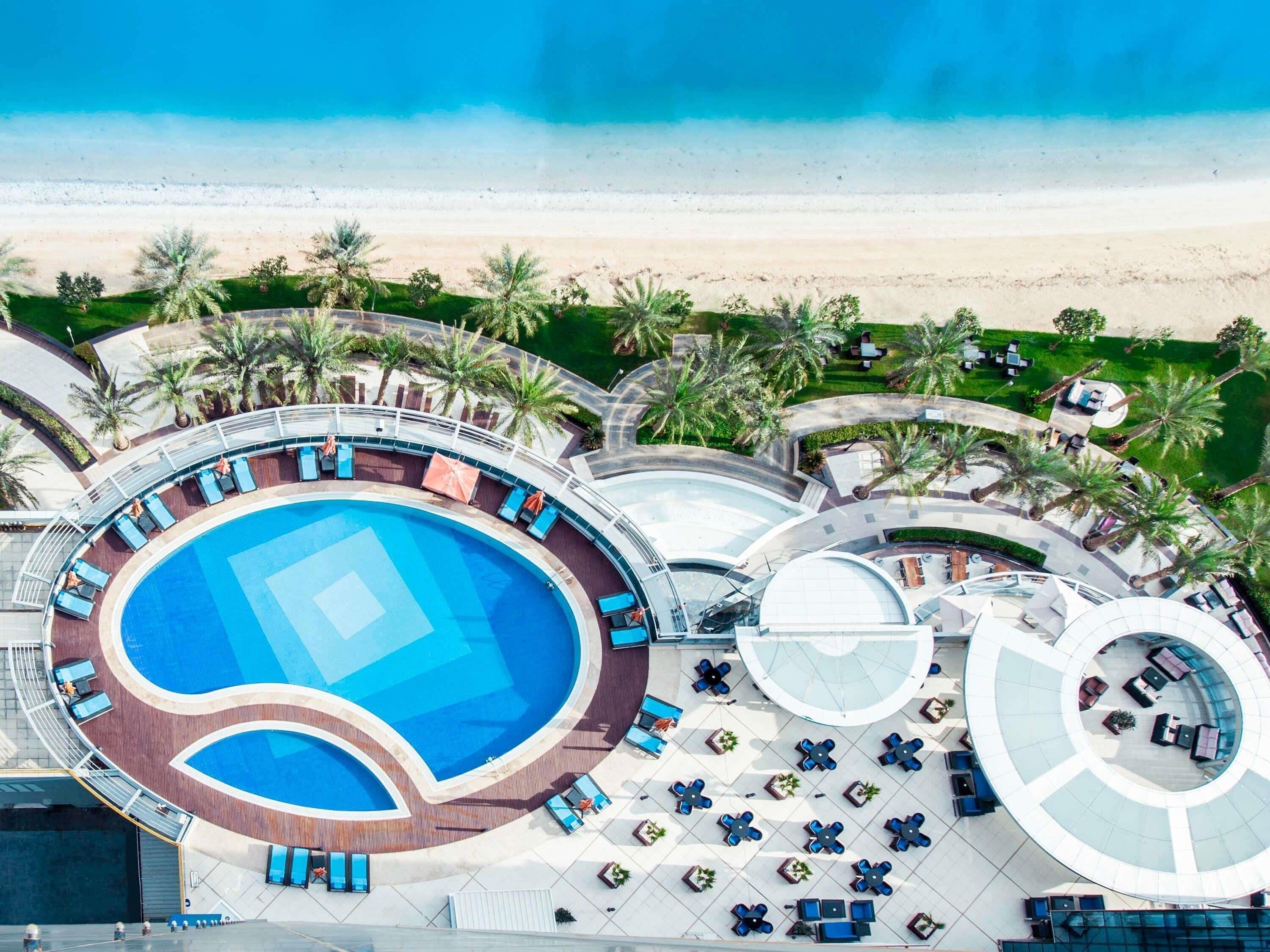 Una piscina al aire libre, sombrillas, sillones reclinables de piscina