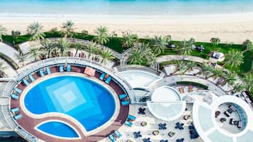 Una piscina al aire libre, sombrillas, sillones reclinables de piscina