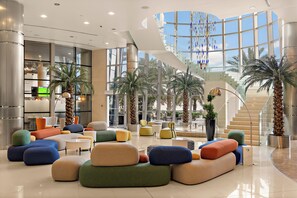 A spacious lobby with a modern staircase, comfortable seating areas, and large windows offering views of palm trees. - Novotel Abu Dhabi Gate (Abu Dhabi)