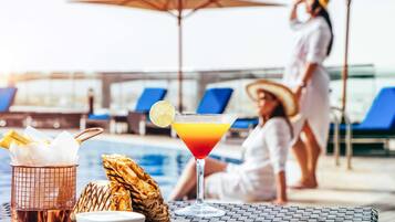 Alberca al aire libre, sombrillas en la alberca y camastros