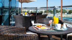 Une terrasse sur le toit, aménagée avec des meubles en osier, des parasols et une table dressée pour le petit-déjeuner.