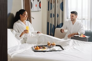 A hotel room with a bed, a tray with breakfast items, and a window with curtains. - Novotel Abu Dhabi Gate (Abu Dhabi)