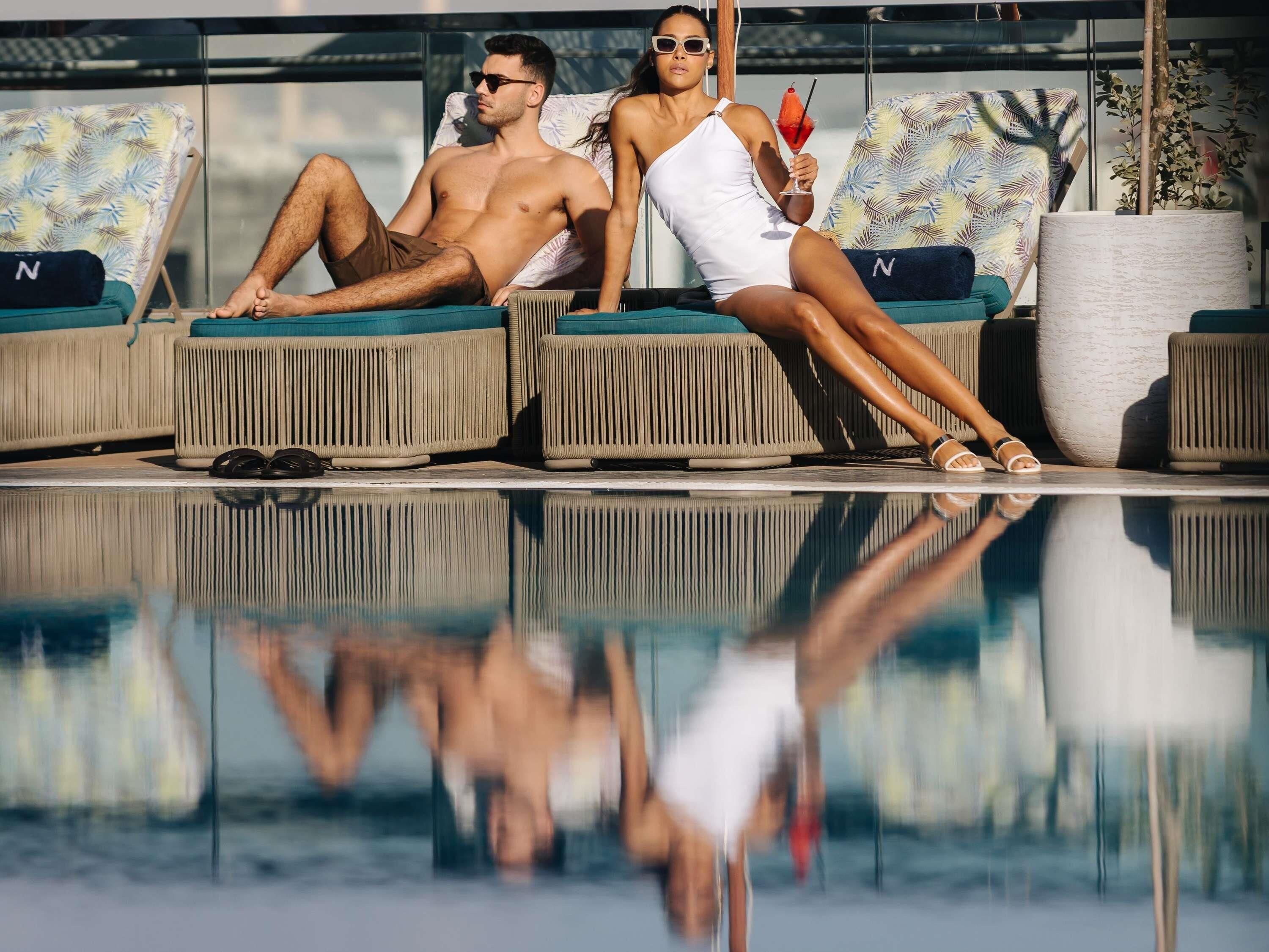 Ein Poolbereich mit Liegestühlen und einem Spiegelbild im Wasser.