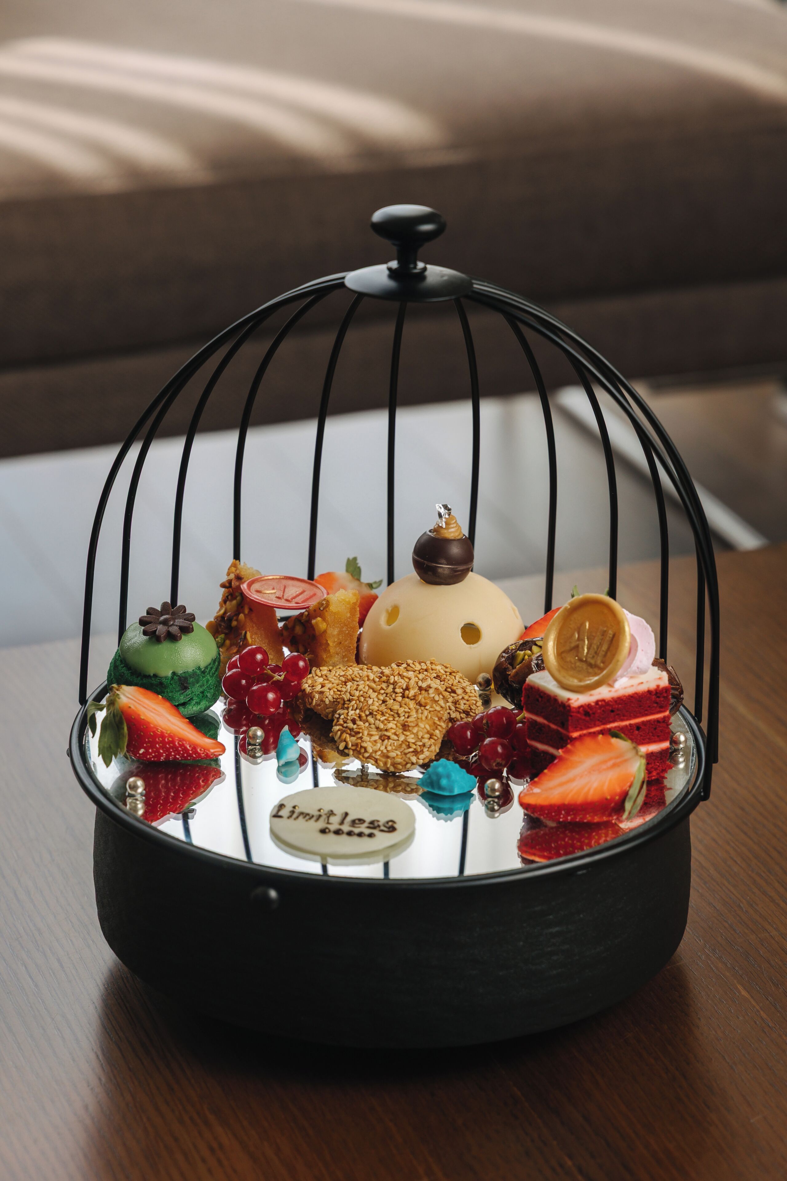 Une présentation de fruits et de desserts dans un panier en fil de fer, posé sur une table en bois.