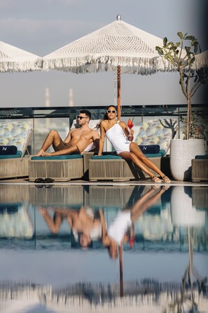 A poolside area with lounge chairs, a large umbrella, and a potted plant. - Novotel Abu Dhabi Gate (Abu Dhabi)