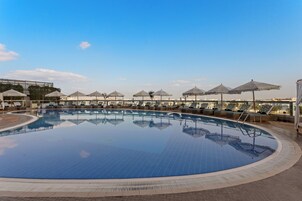 Una piscina al aire libre, sombrillas, sillones reclinables de piscina