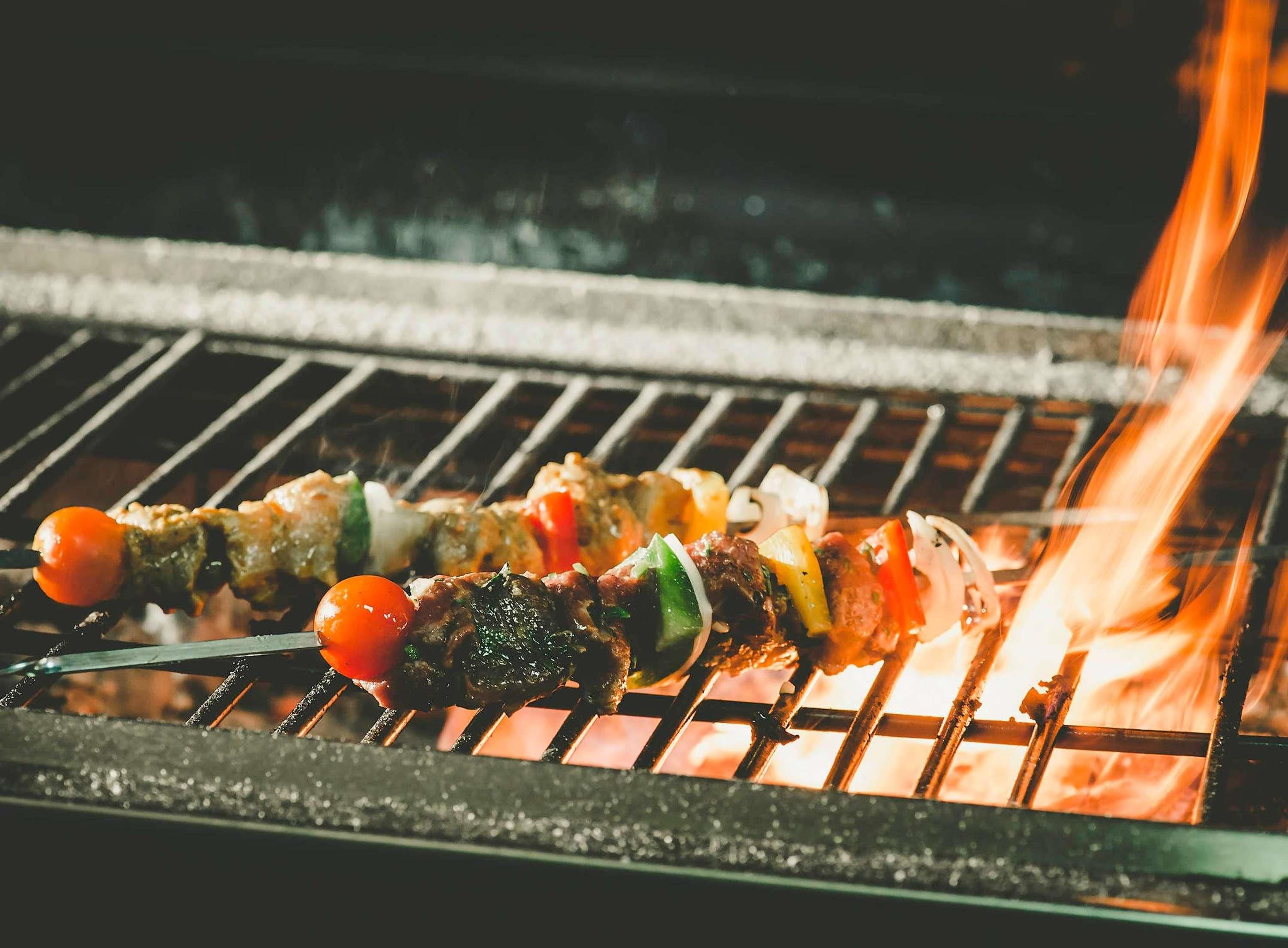 Una parrilla con brochetas de carne y verduras.