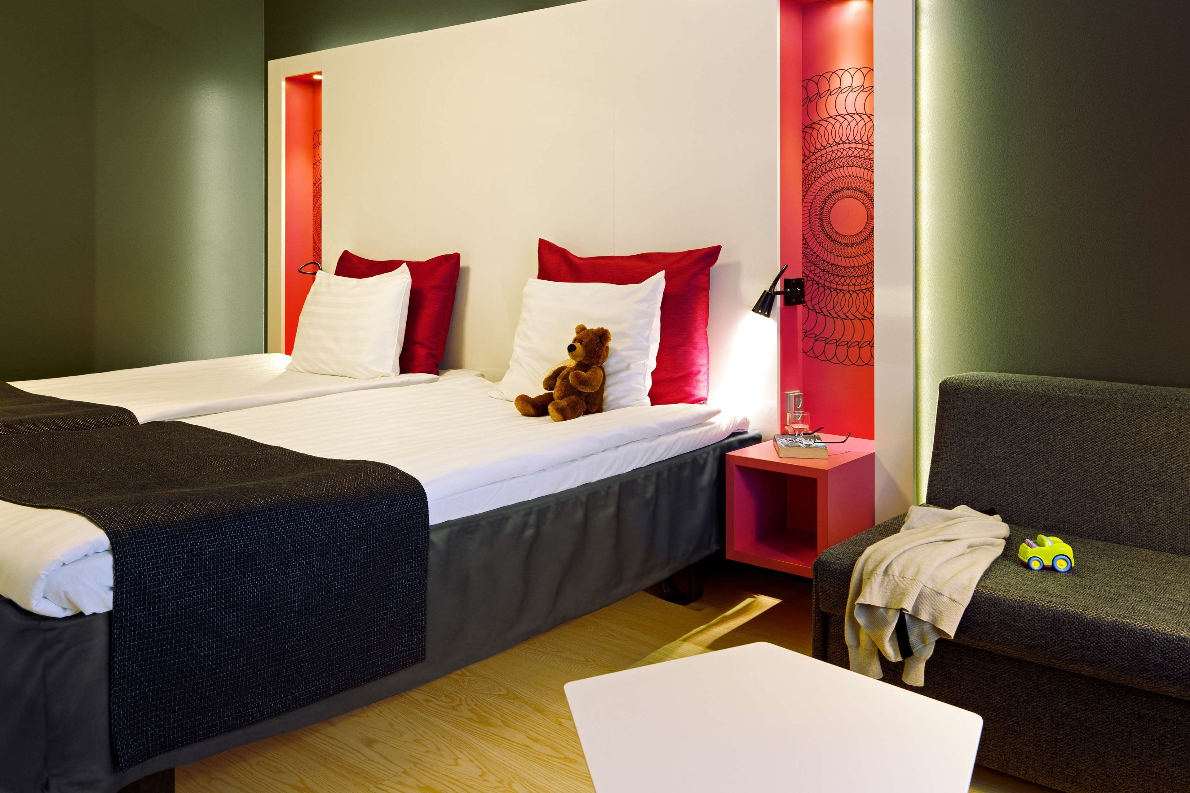Habitación de hotel con dos camas, una mesita de noche, una pequeña mesa y un sofá.
