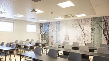 A conference room with tables and chairs, a ceiling with lights, and a mural of trees on the wall.