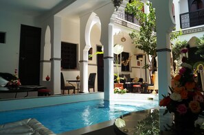 A pool area with a clear view of the pool, white pillars, and surrounding furniture.