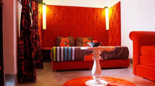 A red-themed room with a bed, a table, and a red armchair.
