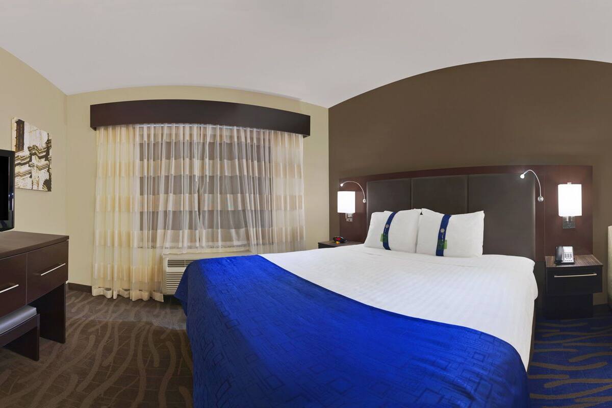 Una habitación de hotel con una cama grande, un escritorio, una silla y un televisor.