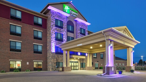 Ein Hotel mit einem gut sichtbaren Schild 'Holiday Inn Express & Suites', einer Ziegel-Fassade und einem überdachten Eingangsbereich.