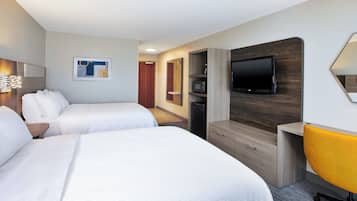 A hotel room with two beds, a TV, a microwave, and a desk with a chair.