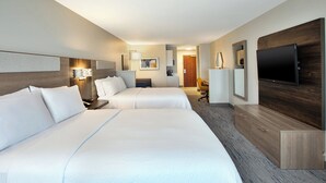 Ein Hotelzimmer mit zwei Betten, einem Fernseher, einem Schreibtisch und einem Stuhl.