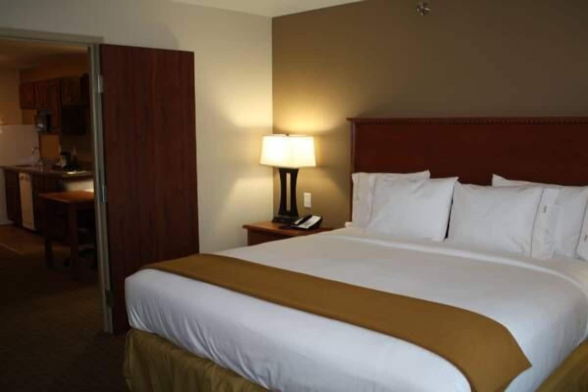A hotel room with a large bed, a bedside table with a lamp, and a wooden headboard.